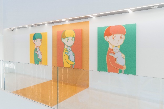 A wall with pictures of a child holding a catDescription automatically generated